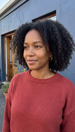 Smiling woman in a red sweater in front of a blue wall
